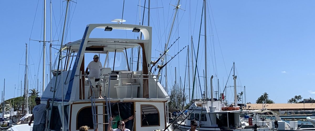 People on a boat named 'Magic' in a marina under a clear blue sky.
